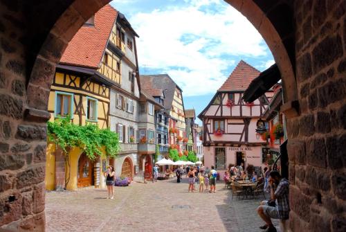 a group of people walking down a street with buildings at Gîte " le Schmoutzi" Duplex centre historique Riquewihr in Riquewihr