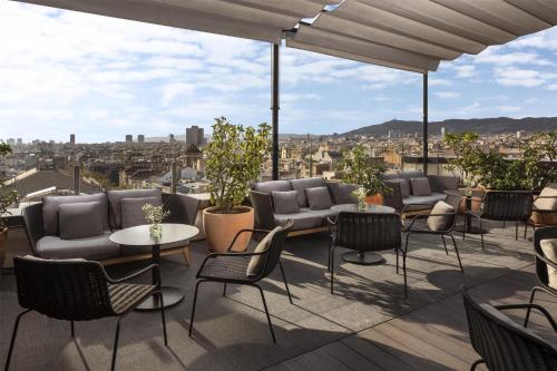 a patio with chairs and tables and a view of a city at NH Collection Barcelona Gran Hotel Calderon in Barcelona