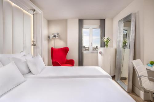 a hotel room with a white bed and a red chair at NH Collection Barcelona Gran Hotel Calderon in Barcelona