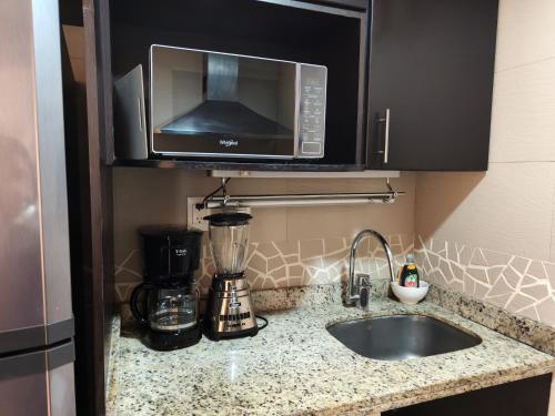 a kitchen counter with a sink and a microwave at Oceanfront Condo in Ixtapa, Zihuatanejo in Ixtapa