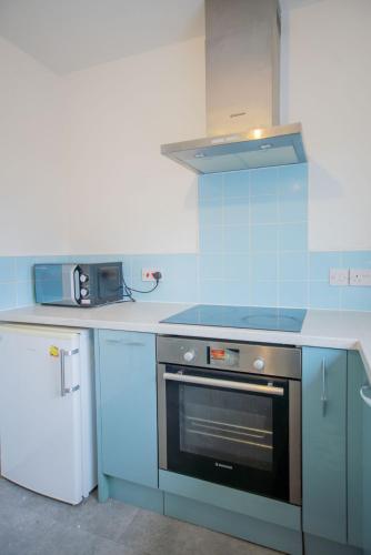 a blue kitchen with a stove and a microwave at Rydal Retreat in Carlisle