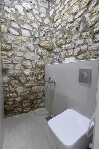 a bathroom with a stone wall and a toilet at Beitkamle in Batroûn
