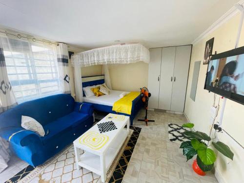 a small room with a blue couch and a bed at Tausi Studio Greenspot in Ruiru