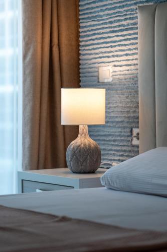 a lamp sitting on a table next to a bed at White Titanic 204 in Mamaia Sat/Năvodari