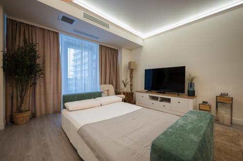 Un dormitorio con una cama y un televisor de pantalla plana. en White Titanic 204, en Mamaia Nord – Năvodari