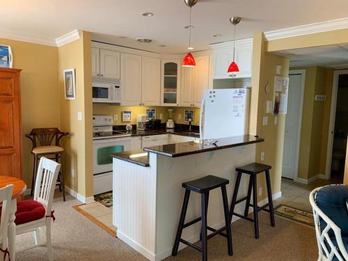 a kitchen with white cabinets and a counter with stools at The crest 403 in Rehoboth Beach