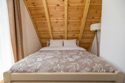 a bed in a room with a wooden ceiling at Žabljak- FamilyOasis in Žabljak