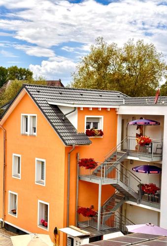 an orange building with balconies and purple umbrellas at Bodensee Sunshine Zimmer & Apts. in Uhldingen-Mühlhofen