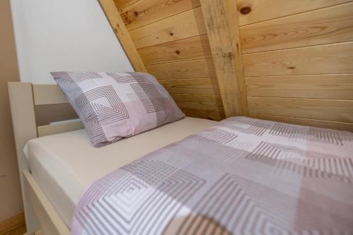 a bed in a room with a wooden wall at Žabljak- FamilyOasis in Žabljak