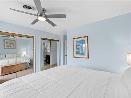 a white bedroom with a bed and a ceiling fan at Seabreeze village 5 in Dewey Beach