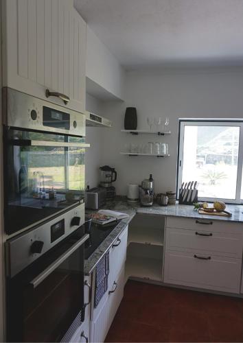 a kitchen with white cabinets and a stove top oven at The Cão & Calf in Faja Grande
