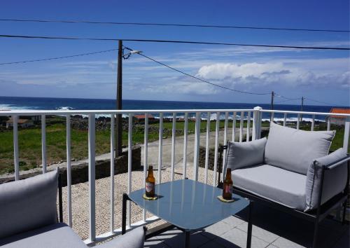 a table and chairs on a balcony with the ocean at The Cão & Calf in Faja Grande