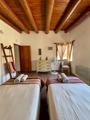 two beds in a room with wooden ceilings at Cabañas La Nochera in Tilcara