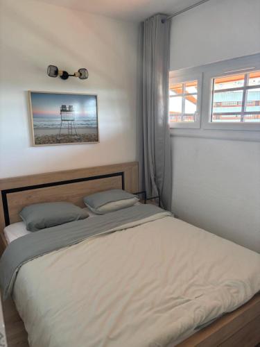 a bedroom with a bed and a window with a picture at Élégant T2 acces direct plage in Saint-Cyprien-Plage