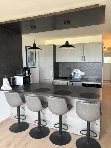 a kitchen with a large black counter and chairs at Élégant T2 acces direct plage in Saint-Cyprien-Plage