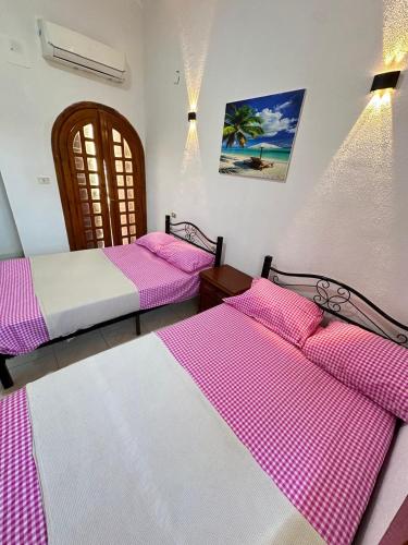 two beds in a room with pink and white sheets at شاليه للايجار في مارينا 5 استمتع بالزياره لا تنسى كود ج4 in El Alamein