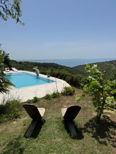 two chairs sitting in the grass near a swimming pool at Villa Ela - Cape of Rodon in Draçi