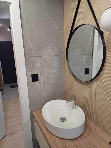 a bathroom with a white sink and a mirror at Apartament JUST LIVING in Pleszew