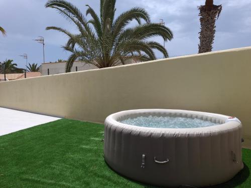 a large metal tub sitting on the grass next to a wall at Mirador de Sotavento apartment 8241 in Costa Calma