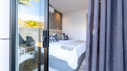 a bedroom with a bed and a sliding glass door at The Hyacinth at Arbour Nature Estate in George