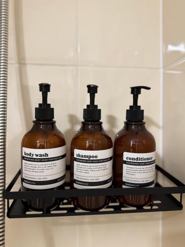 three bottles of soap on a shelf in a bathroom at Zelena Luxurious Apartment, Private Parking, Fast Wi-Fi, Self Check-In Anytime Perfect For Late Arrivals, 5 Minutes to Old Trafford Stadium in Manchester