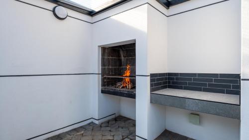 a fireplace in a white room with a fire in it at The Hyacinth at Arbour Nature Estate in George