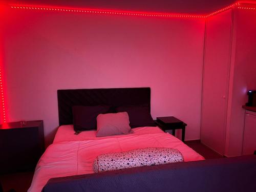 a red room with a bed with a pink wall at Studio 5 minutes RER A in Noisy-le-Grand