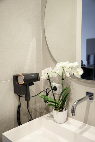 a bathroom sink with a mirror and white flowers on it at Studio Venice Mestre Centrale in Venice