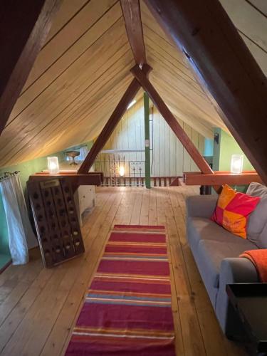 an attic room with a couch and a rug at Badehaus Villa Fiedrichs in Ilmenau