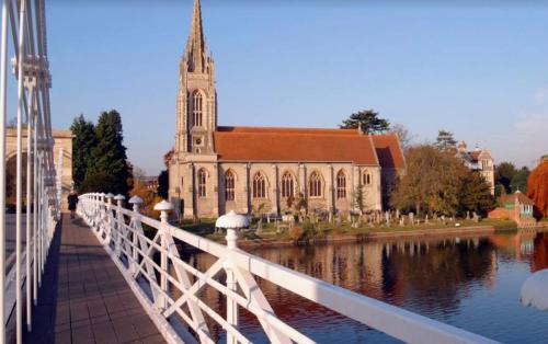 a bridge over a river with a church and a building at Chic Marlow Escape - Courtyard, River and Fun! Near Windsor and Henley in Marlow