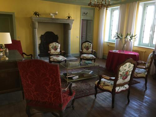 a living room with chairs and a table and a fireplace at Le Vieux Colombier in Pouzy-Mésangy