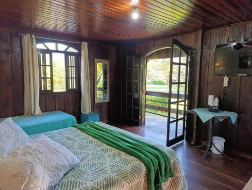 a bedroom with a bed with a green blanket on it at Pousada e Restaurante Dona Siroba in Morretes