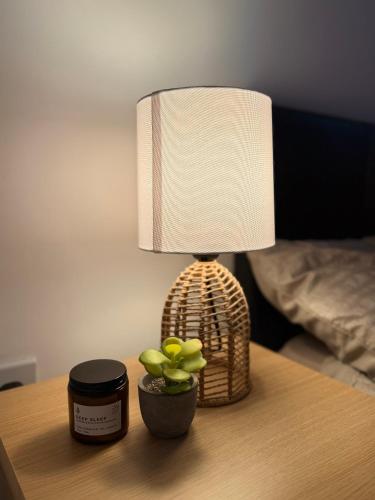 a lamp on a table with a potted plant on it at Zelena Luxurious Apartment, Private Parking, Fast Wi-Fi, Self Check-In Anytime Perfect For Late Arrivals, 5 Minutes to Old Trafford Stadium in Manchester