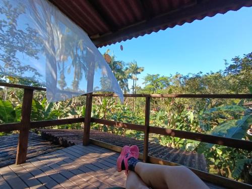 a person sitting on a porch with their feet in pink shoes at Pousada e Restaurante Dona Siroba in Morretes