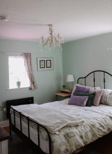 a bedroom with a bed with purple pillows and a chandelier at Lime cottage in Kilrush