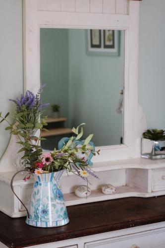 a vase with flowers on a counter in front of a mirror at Lime cottage in Kilrush
