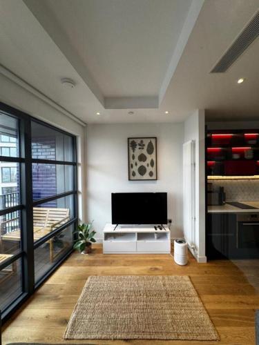 a living room with a flat screen tv and a kitchen at London Iconic View Retreat in London