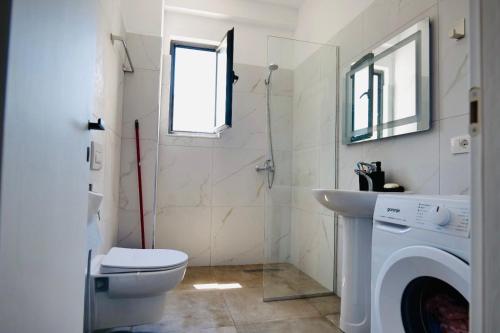 a bathroom with a toilet a sink and a washing machine at Aren Suite in Vlorë