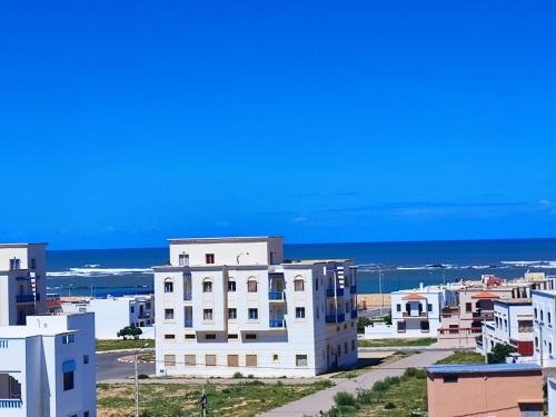a city with white buildings and the ocean in the background at La maison bleu in Oulad Akkou