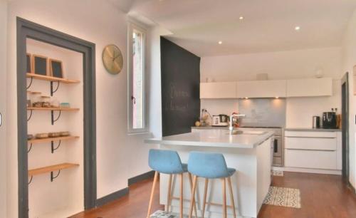 a kitchen with a counter and two blue stools at Grande maison centre ville in Laval