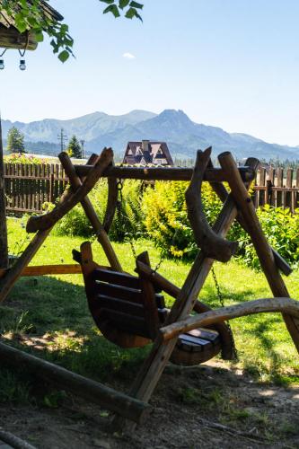 a wooden bench in the grass with mountains in the background at TATRA COTTAGE góralski domek z kominkiem in Murzasichle