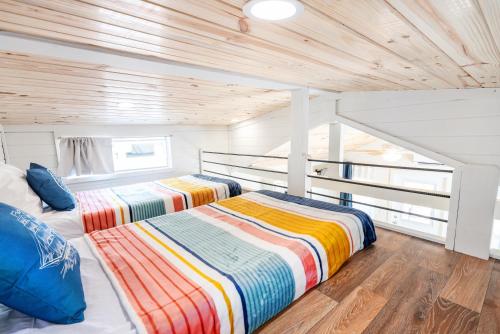 two beds in a room with wooden ceilings at 4 Heron Haus, Luxury Tiny House, Pet Friendly, Mins to Downtown Guntersville in Guntersville