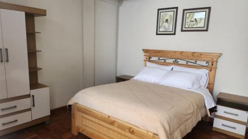 a bedroom with a bed with a wooden headboard at Departamento entero soleado in Sucre