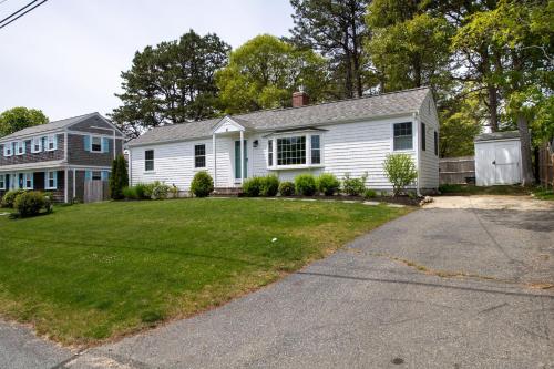 a white house with a yard at Cape Cod Cottage by Leavetown Vacations in Dennis Port