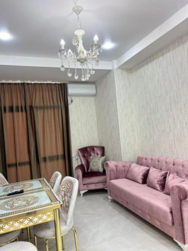 a living room with pink furniture and a chandelier at Comfortable 5 rooms apartment in Kutaisi