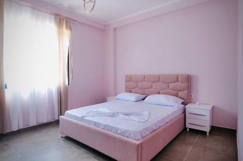 a bedroom with a pink bed with a pink headboard at Aren Suite in Vlorë