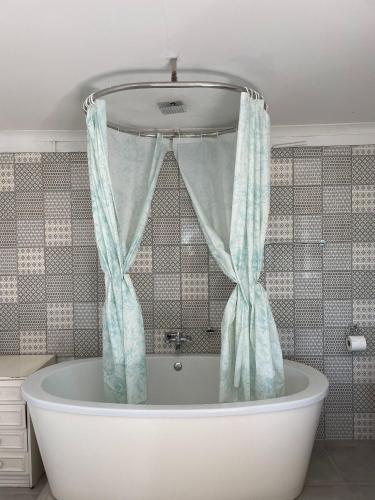 a bath tub with a shower curtain in a bathroom at Honeymoon Stay at The James Family Farm in Grabouw