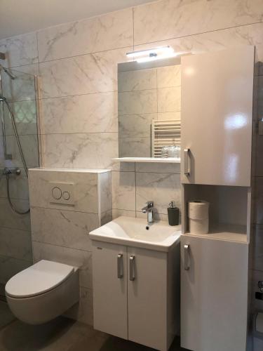 a white bathroom with a toilet and a sink at Sobe apartma Dobe in Bled