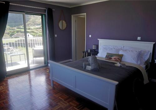 a bedroom with a large bed and a balcony at The Cão & Calf in Faja Grande