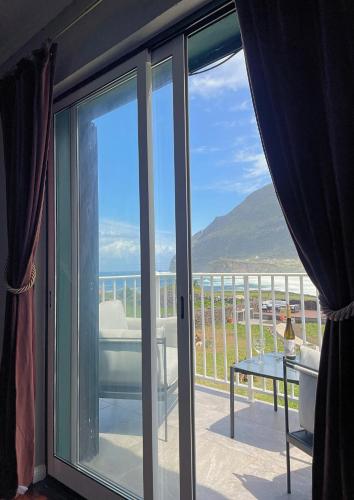 a balcony with sliding glass doors with a view of the ocean at The Cão & Calf in Faja Grande